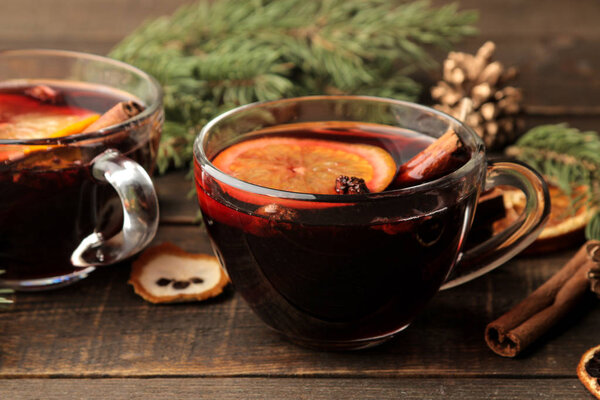 Hot mulled wine with cinnamon and orange in glass cups and Christmas decorations on a dark background. Christmas. new Year.