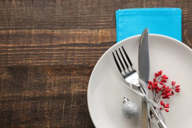 Noel tablo ayarı. Bıçak, çatal ve mavi peçete ile plaka. kahverengi ahşap bir masa üzerinde. üstten görünüm ile bir yazıt için yer. Yeni yıl. tatil