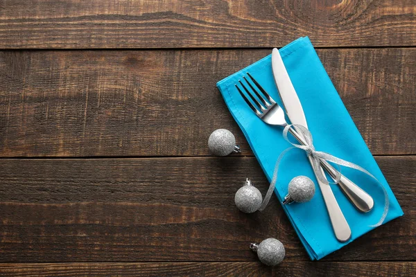Christmas table setting. Knife and fork with blue napkin. on a brown wooden table. top view with space for an inscription. new Year. holidays