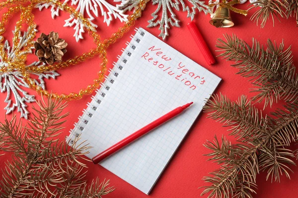 inscriptions New Year\'s resolution in a notebook and various New Year\'s decorations on a red background. New Year Christmas. holidays