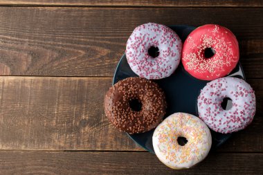 Krema ve kahverengi ahşap bir masa üzerinde bir tabakta yağmurlama ile çeşitli tatlı çörek. yukarıdan görüntüleyin. metin için ile yer