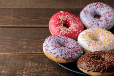 Krema ve kahverengi ahşap bir masa üzerinde bir tabakta yağmurlama ile çeşitli tatlı çörek. metin için ile yer