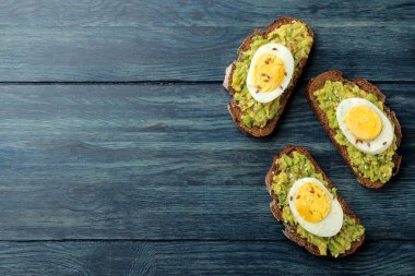 Avokado püresi ve metin için yer ile mavi ahşap bir masa üzerinde yumurta ile sandviç. yukarıdan görüntülemek