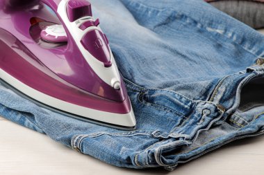 Lila demir ve kot pantolon beyaz bir tablo. elbise Ütü. eşyaları elektrikli ev aletleri.