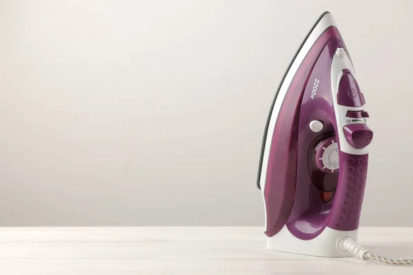 lilac iron on a light background. ironing clothes. household electrical appliances.