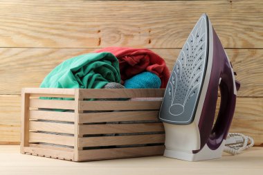 Lila demir ve giyim doğal ahşap zemin üzerine bir kutu içinde bir yığın. elbise Ütü. eşyaları elektrikli ev aletleri.