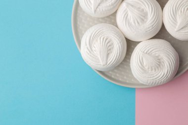 Tatlı beyaz hatmi bir parlak şık mavi ve pembe arka plan üzerinde bir tabakta. Tatlılar. tatlı. metin için yer ile üstten görünüm