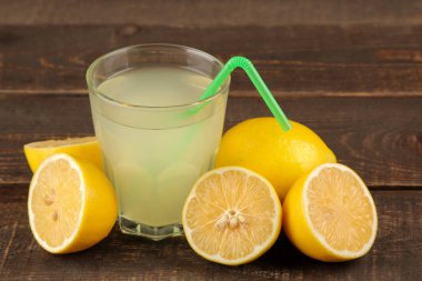 Narenciye meyve suları. limon suyu bir bardak kahverengi ahşap bir masa üzerinde taze limon ile