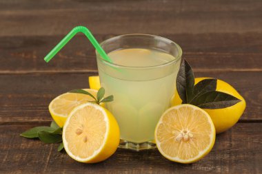 Narenciye meyve suları. limon suyu bir bardak kahverengi ahşap bir masa üzerinde taze limon ile
