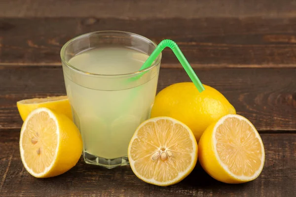 Citrus juices. lemon juice in a glass with fresh lemons on a brown wooden table
