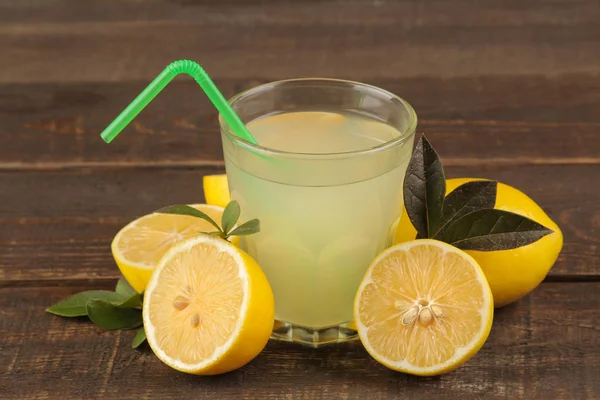 Citrus juices. lemon juice in a glass with fresh lemons on a brown wooden table