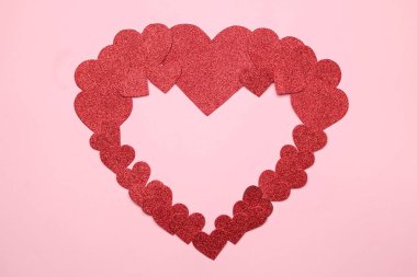 Büyük bir kalbi parlak pembe bir arka plan üzerinde küçük kırmızı kalplerin. çerçeve kalplerin, metin için yer ile üstten görünüm