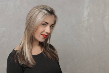 Güzel kız kırmızı dudaklı ve siyah bir elbise. dikey gri beton duvar arka plan üzerinde. duygu. farklı pozlar