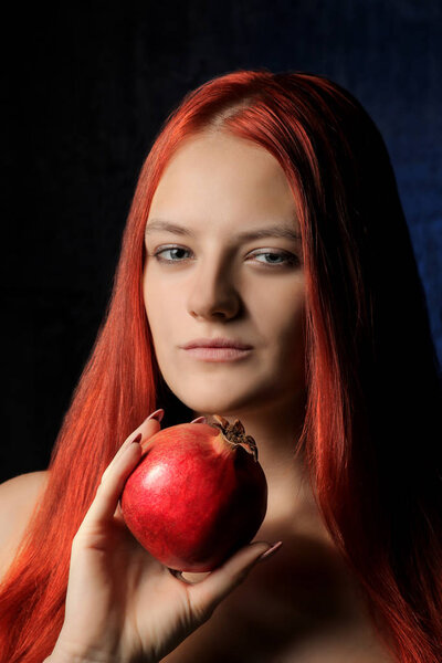 портрет красивой девушки с рыжими волосами и гранатовыми фруктами на фоне синей стены. различные позы
.