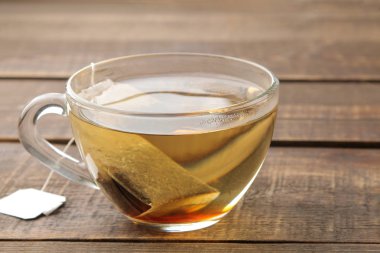 Kahverengi ahşap arka plan üzerinde bir cam fincan çay poşeti. çay yapmak için