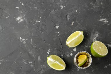 Altın tekila bir cam cam tuz ve limon ile siyah bir beton zemin üzerine vurdu. Bar. alkollü içecekler. metin için yer ile üstten görünüm