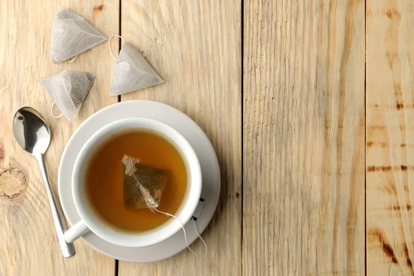 紅茶ティーバッグ ピラミッドとカップ クローズ アップ 木製のテーブル お茶をする — ストック写真
