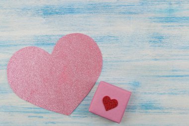Pembe parlak kalp ve ahşap arka plan mavi bir hediye. yukarıdan görüntüleyin. metin için yer. Sevgililer günü