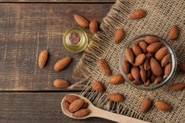 bir cam kase ve kahverengi ahşap bir masa taze badem fındık doğal badem yağı. üstten görünüm