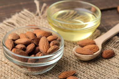 cam bir kase ve kahverengi ahşap bir masa üzerinde taze badem fıstığı doğal badem yağı. 