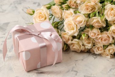 Güzel ihale mini gül ve hafif bir beton zemin üzerine bir hediye kutusu bir buket. tatil. sunar