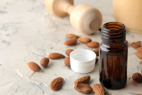 natural cosmetic almond oil in a glass jar and fresh almond nuts on a light concrete background. close-up