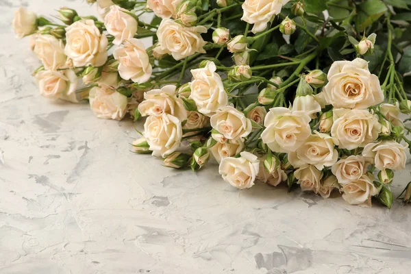 A bouquet of beautiful tender mini roses on a light concrete background. space for text