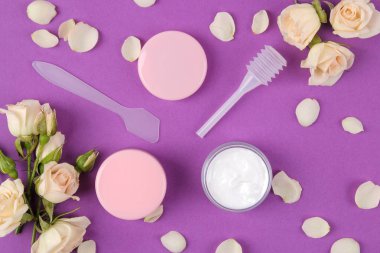 Kozmetik için yüz ve vücut parlak mor zemin üzerine taze gül pembe şişelerde. Spa. üstten görünüm