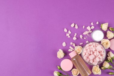 Kozmetik için yüz ve vücut parlak mor zemin üzerine taze gül pembe şişelerde. krem ve losyon, deniz tuzu ve sabun. Spa. yukarıdan görüntüleyin. metin için yer