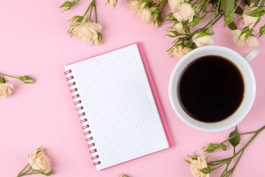 Bir fincan kahve ve parlak pembe bir arka plan üzerinde bir not defteri ile güzel mini gül. tatil. Sevgililer günü. Kadınlar günü. üstten görünüm.