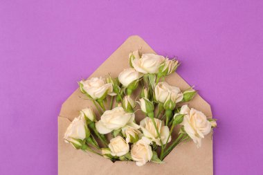 Güzel mini gül parlak mor arka plan üzerinde zarf içinde. tatil. Sevgililer günü. Kadınlar günü. üstten görünüm.