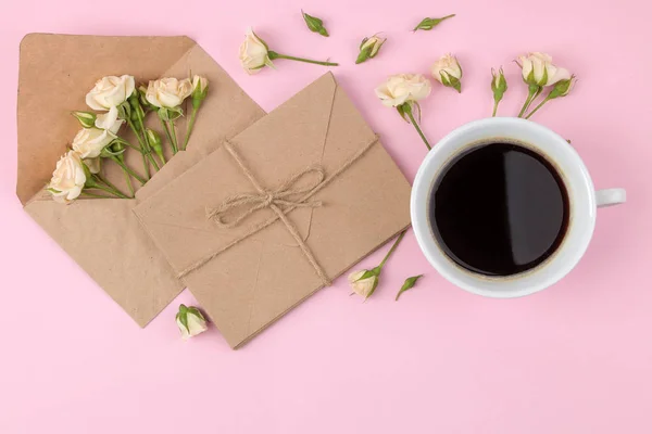 Beautiful mini roses a cup of coffee and an envelope on a bright pink background. holidays. Valentine\'s Day. women\'s Day. top view.