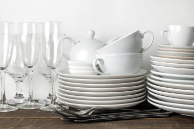 Bulaşık yığını. Sofra üzerinde kahverengi ahşap bir masa. tablo hizmet için yemekler. tabak ve çatal bıçak takımı, bardak ve çaydanlık, gözlük.