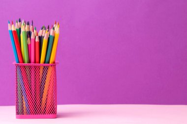 Birçok renkli kalemler parlak trendy leylak arka plan üzerinde pembe bir cam. metin için yer