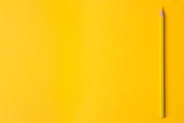 Parlak bir trendy sarı zemin üzerine sarı bir kalem ile kompozisyon. üstten görünüm. metin için yer