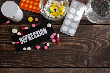 Depresyon kavramı. bir bardak su depresyon kağıt üzerinde ve ahşap bir kahverengi masa haplarla yazı. üstten görünüm