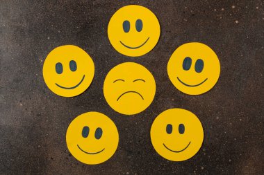 Depresyon kavramı. karanlık bir arka plan üzerinde komik suratlar arasında üzgün smiley. üstten görünüm