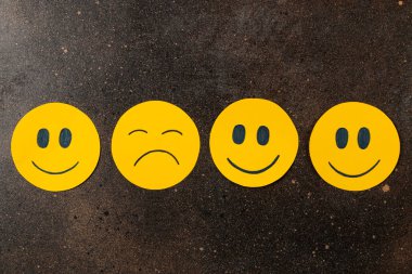 Depresyon kavramı. karanlık bir arka plan üzerinde komik suratlar arasında üzgün smiley. üstten görünüm