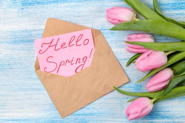 Güzel buket Pembe Lale çiçeklerin hediye kutusu ve metin Merhaba bahar mavi ahşap arka plan üzerinde zarf kağıt üzerinde. Yukarıdan görüntüleyin. Bahar. tatil.
