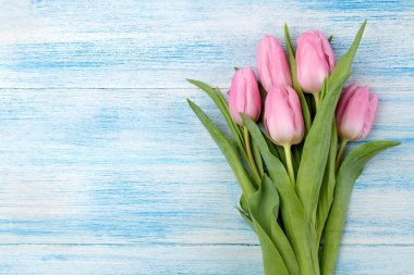 Güzel bir buket Pembe Lale çiçek mavi ahşap arka plan üzerinde çerçeve. Üstten Görünüm. metin bahar için alan. tatil.
