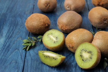 Lezzetli olgun birçok kivi ve kivi mavi ahşap bir masa bir kesim içinde.