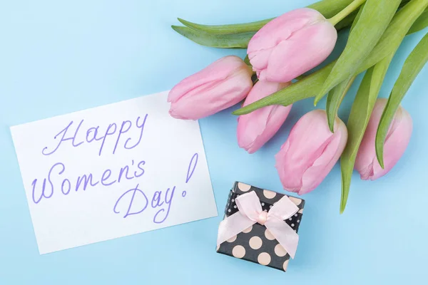 一束美丽的粉红色郁金香花和一个礼品盒在一个时尚明亮的蓝色背景 短信快乐的妇女日 从上面看 — 图库照片