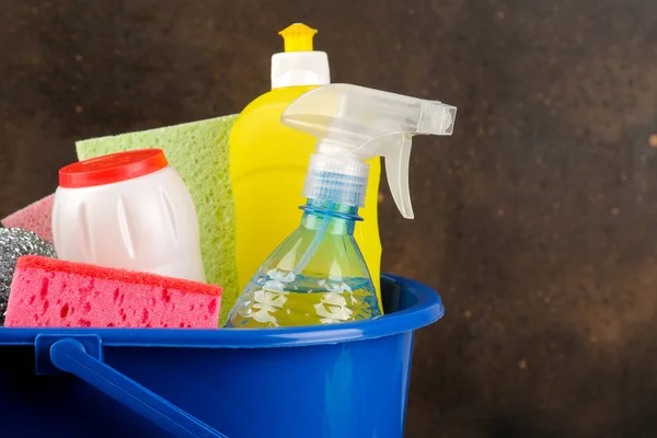 Bottles with cleaning products and detergents in a blue bucket on a dark background. cleaning. cleaning products