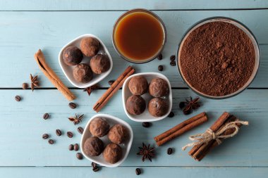 çeşitli çikolatalar. şeker topları çikolata Mavi ahşap bir masa üzerinde farklı türde. kakao, tarçın, yıldız anason ve kahve çekirdekleri. Üstten Görünüm