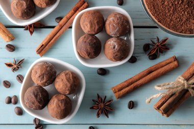 çeşitli çikolatalar. şeker topları çikolata Mavi ahşap bir masa üzerinde farklı türde. kakao, tarçın, yıldız anason ve kahve çekirdekleri. Üstten Görünüm