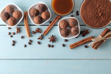 çeşitli çikolatalar. şeker topları çikolata Mavi ahşap bir masa üzerinde farklı türde. kakao, tarçın, yıldız anason ve kahve çekirdekleri. Yukarıdan görüntüleyin. boş alan