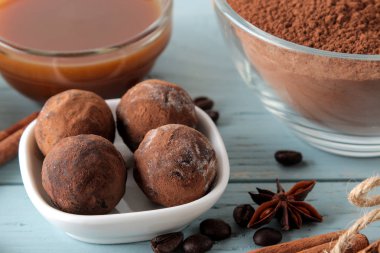 çeşitli çikolatalar. şeker topları çikolata Mavi ahşap bir masa üzerinde farklı türde. kakao, tarçın, yıldız anason ve kahve çekirdekleri.