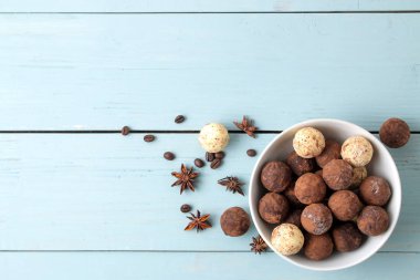 çeşitli çikolatalar. şeker topları çikolata Mavi ahşap bir masa üzerinde farklı türde. kakao, tarçın, yıldız anason ve kahve çekirdekleri. Yukarıdan görüntüleyin. boş alan