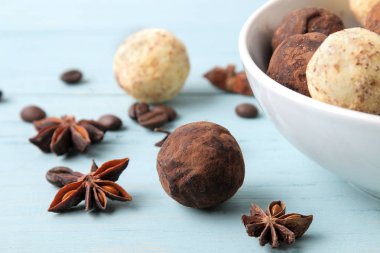 çeşitli çikolatalar. şeker topları çikolata Mavi ahşap bir masa üzerinde farklı türde. kakao, tarçın, yıldız anason ve kahve çekirdekleri.