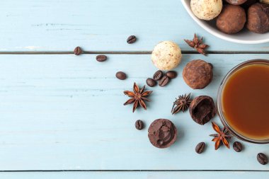 çeşitli çikolatalar. şeker topları çikolata Mavi ahşap bir masa üzerinde farklı türde. kakao, tarçın, yıldız anason ve kahve çekirdekleri. Yukarıdan görüntüleyin. boş alan